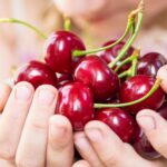summer-the-girl-is-holding-a-ripe-red-cherry-in-2025-10-15-20-38-59-utc
